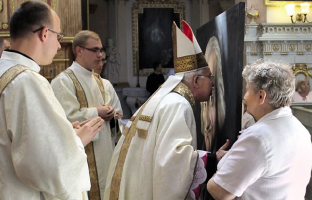 Bp Paweł Socha całuje obraz św. Jana Marii Vianneya, patrona kapłanów