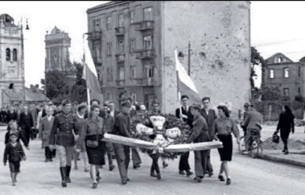 Ryszard Witkowski, Warszawa, 1 sierpnia 1945. Obchody pierwszej rocznicy wybuchu
Powstania Warszawskiego. Złożenie wieńca na zbiorowej mogile powstańczej w parku Dreszera. Widoczne ruiny kościoła św. Michała Archanioła (ul. Puławska 95). Fotografia udost