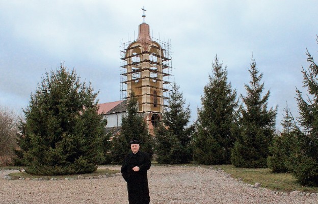 Ks. Andrzej Tomys na tle wieży kościoła pw. Najświętszego Zbawiciela w Gorzowie