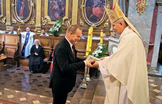 Biskup Jan wręcza medal 850-lecia bazyliki organiście Mariuszowi Bednarzowi