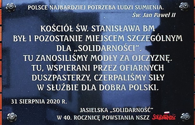 Tablica  poświęcona bł. ks. Jerzemu Popiełuszce i jasielskiej Solidarności znajdują się na zewnętrznej ścianie kościoła